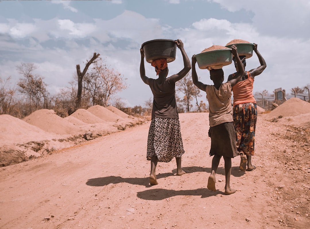 Photograph showing threewomencarryingbasinwhilewalkingbarefoot — illustrating international aid programmes in Africa
